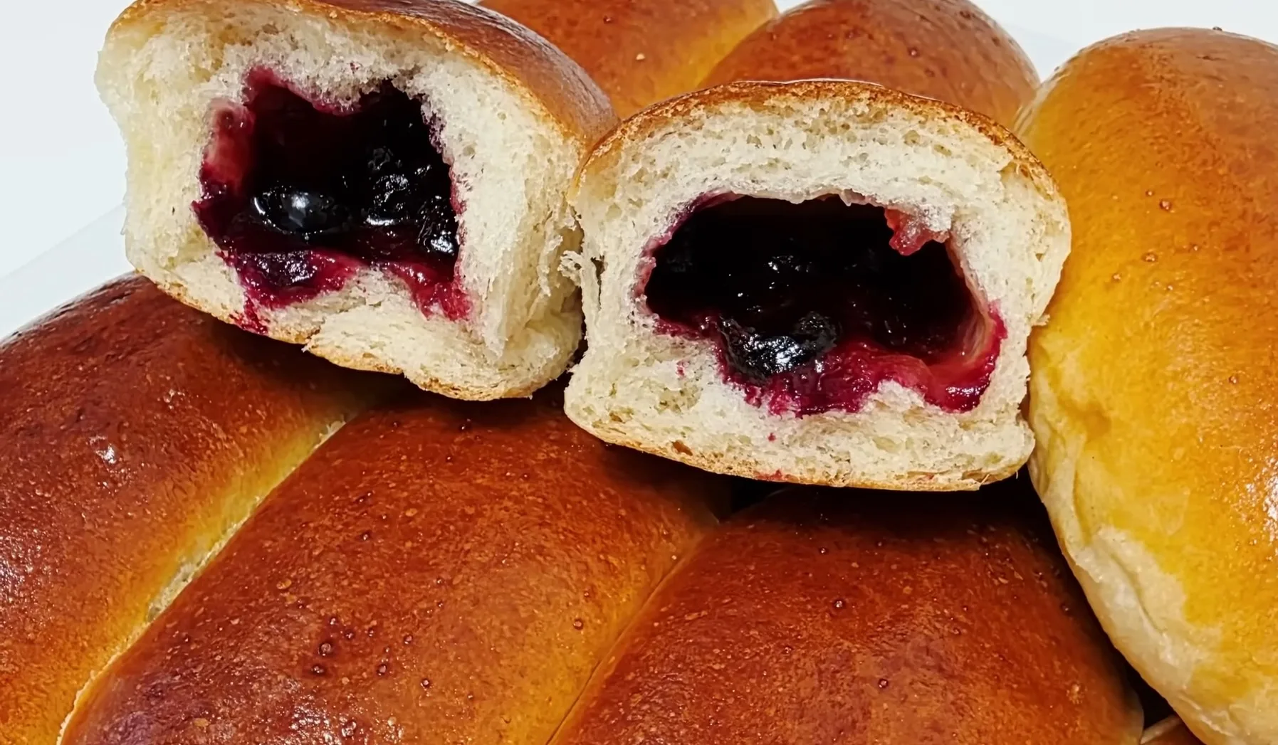 Домашние пышные пирожки с замороженной смородиной и повидлом в разрезе на противне