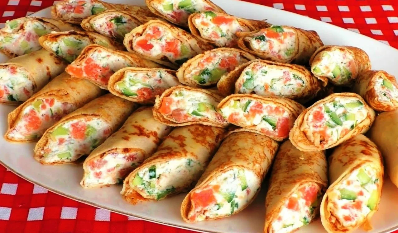 Тонкие золотистые блинчики с очень вкусной начинкой на тарелке