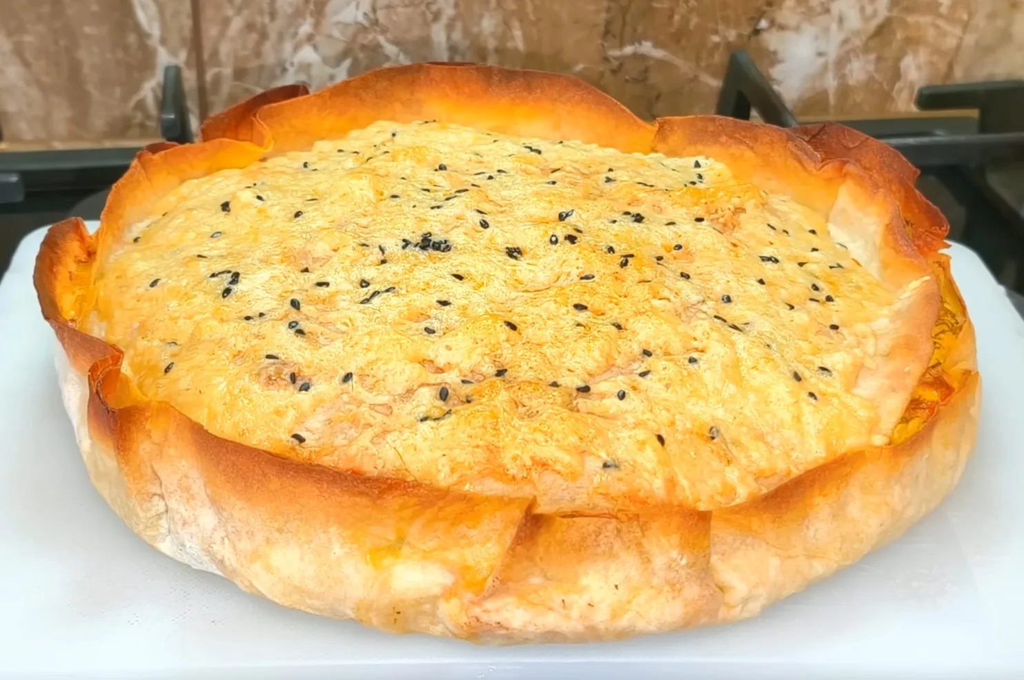 Золотистый рыбный пирог из лаваша с тунцом и кунжутом на тарелке — рецепт Виктора Ерофеева